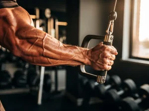 Atleet grijpt kabelapparaat handvat tijdens rep, gespannen onderarmspieren zichtbaar in moderne sportschool met natuurlijk licht.