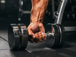 Gespierde onderarm en bicep in maximale contractie tijdens een dumbbell curl, dramatische zijverlichting benadrukt spierdefinitie.